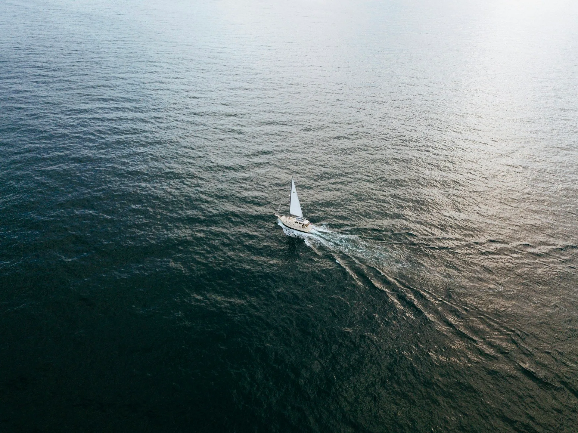 A sailing yacht crossing open water, photographed from above